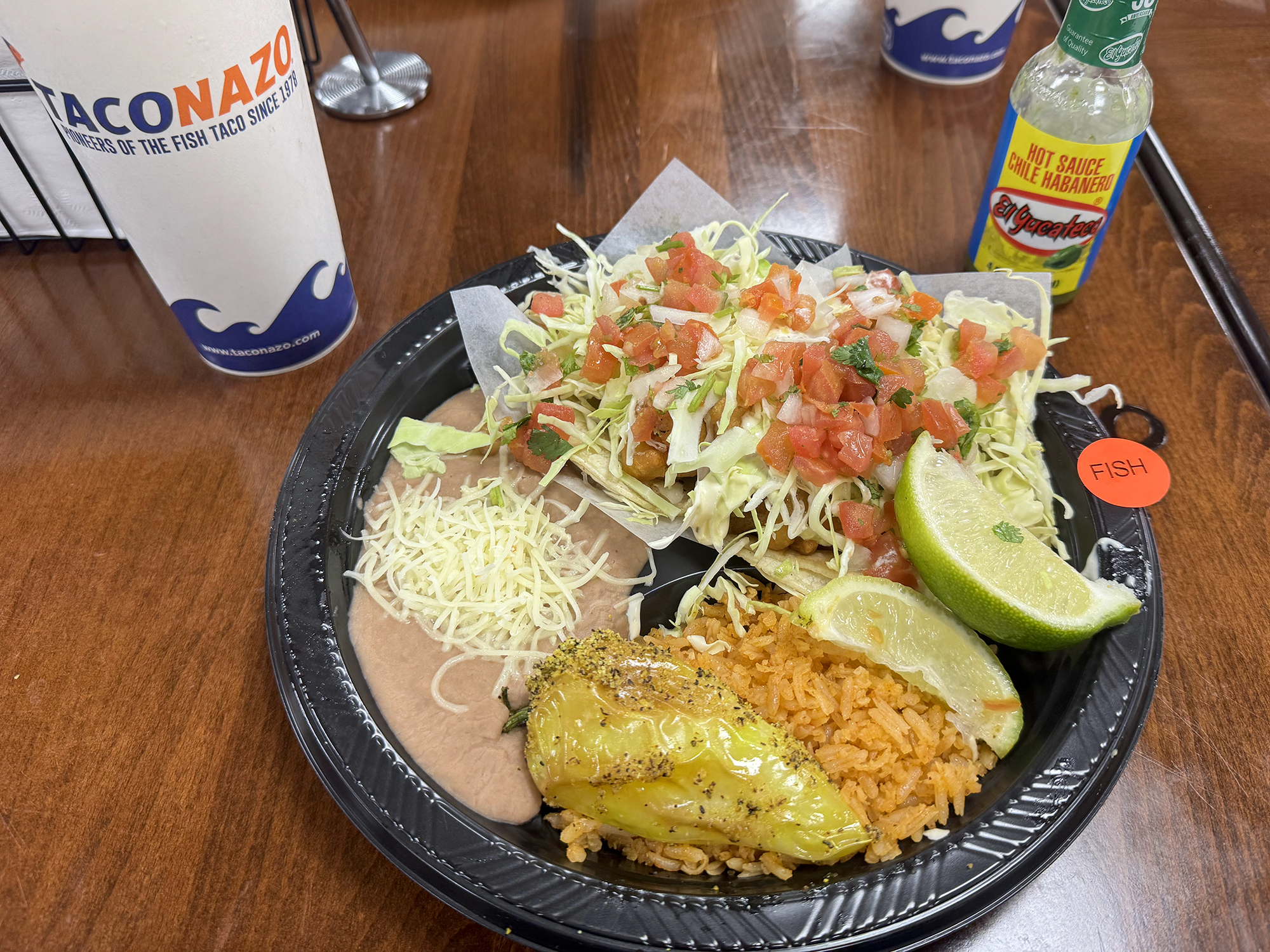 Delicious plate of fish tacos with rice, beans and a roasted pepper.