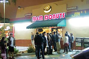 Long line of patrons waitings outside the M&M Donuts shop in the middle of the night.