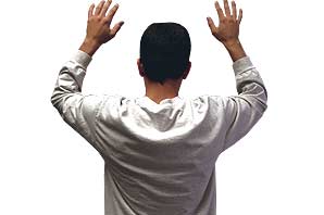 A traveler with his hands raised above his shoulder in position to be padded down by Airport Security