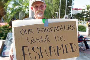 Terry Lee holding a hand written sign "OUR FORFATHERS Would be ASHAMED".