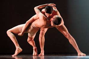 Two male dancers intertwined in an intricate position on stage