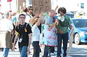 Protestors on the street carrying hand written signs such as "End the FED" and "Respect existence or expect resistance". One protestor was carrying a microphone loudspeaker.