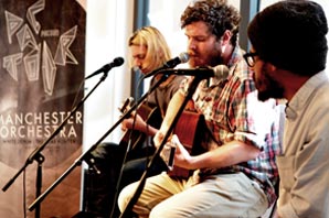 Three members of the Manchester Orchestra performing with two of them playing guitar.