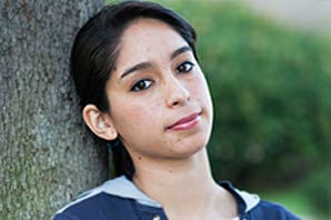 Karla Perez in a relaxed mood while leaning against a tree.