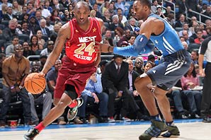 Kobe Bryant in red jersey number 24 carrying the basketball guarded by Dwight Howard in blue jersey.