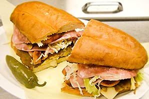 A plate of stacked Torta Chilanga sandwich and a Jalapeno.