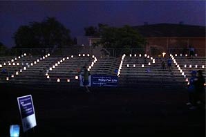 A night shot of an athletic field with light-bulb spelling the word HOPE glowing under the night sky.