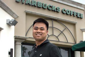 Chris Nyuyen wearing Starbuck's dark green collar shirt, standing and smiling in front of a Starbuck's Coffee.