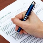 A student holding a ball point pen filling the USU-2012-13-AC-GRANT-APPLICATION form.