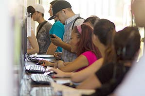 Side view of a full line of students standing in front of registration terminal taking care of registration and/or changing class programs at Santa Ana College Administration Building.