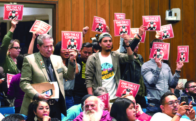 As councilmembers discussed the issue at the March 7 meeting, Santa Ana residents stood holding signs in dissaproval of possibly renewing the city’s contract with Immigrations and Customs Enforcement.