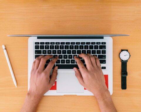 person using macbook pro on brown wooden table