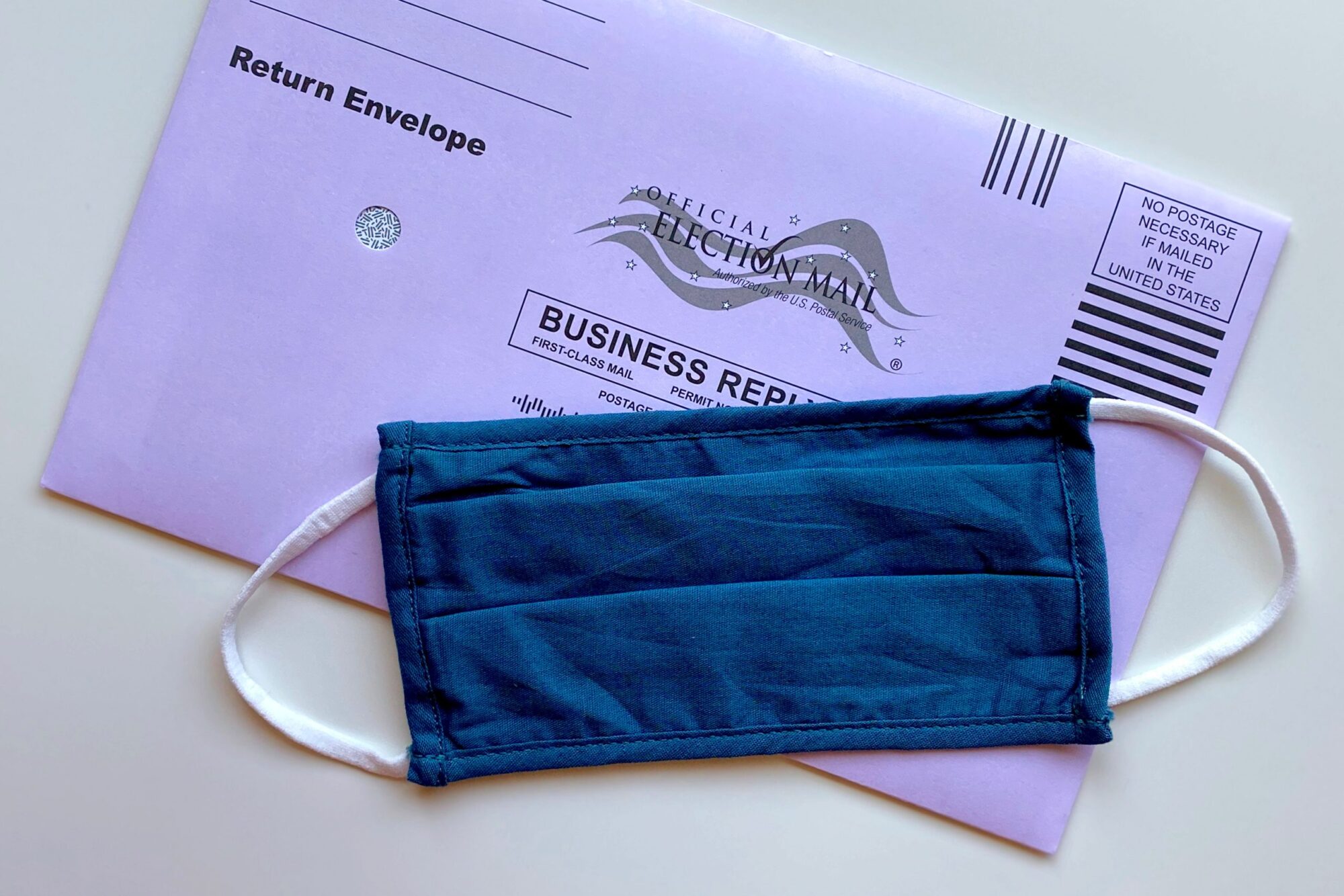 A cloth mask covering a mail-in ballot.