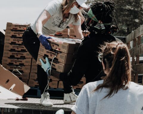 woman in white t-shirt and blue denim jeans sitting on brown cardboard box