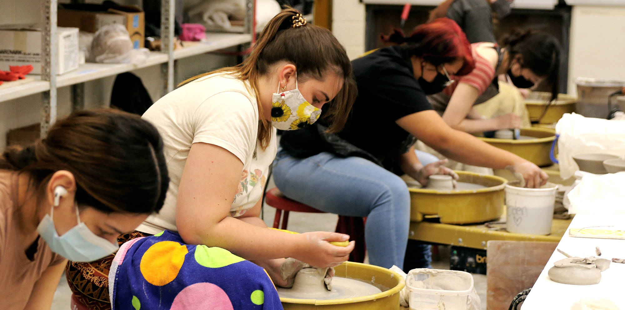 Ceramics students behind the throwing wheel.