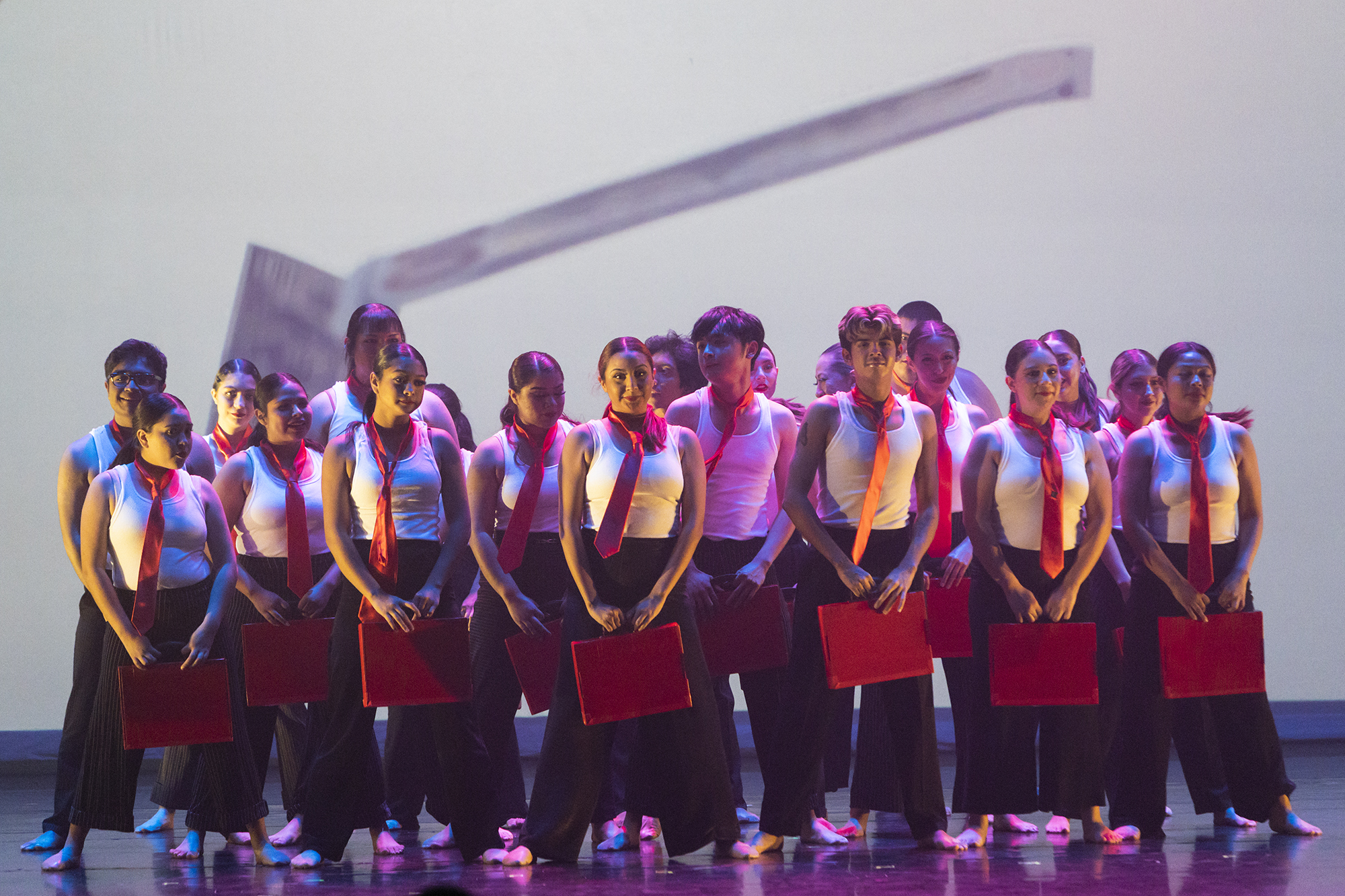group of dancers on stage with hammer projection behind them 
