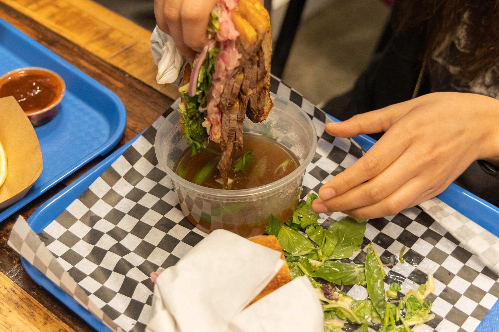 Pho brisket on rye being dunked in the beef consommé