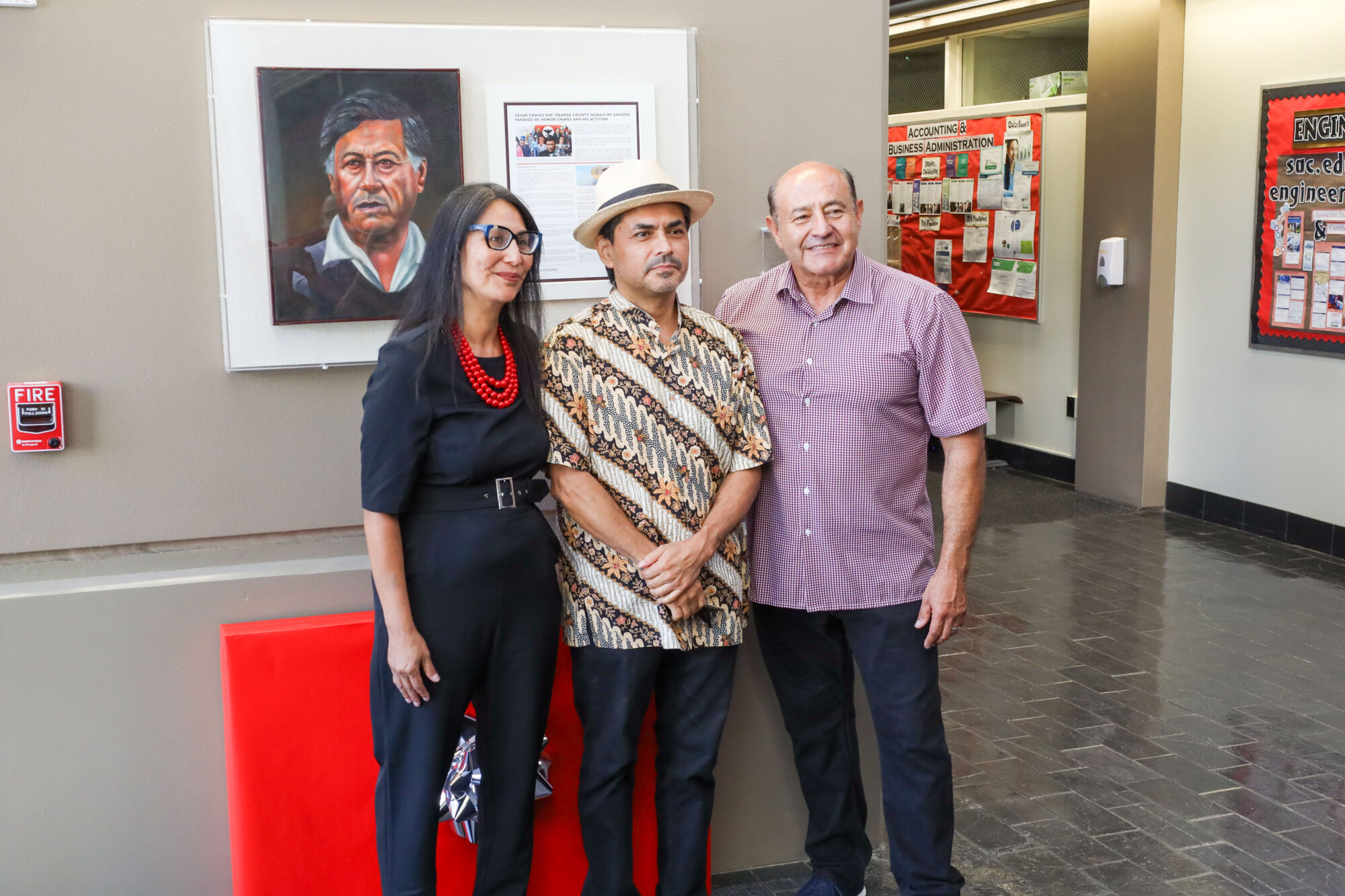 Three people standing in front of a mural