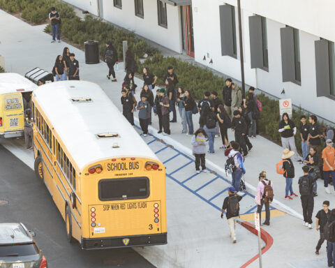 High school students boarding buses and transit vans to go home