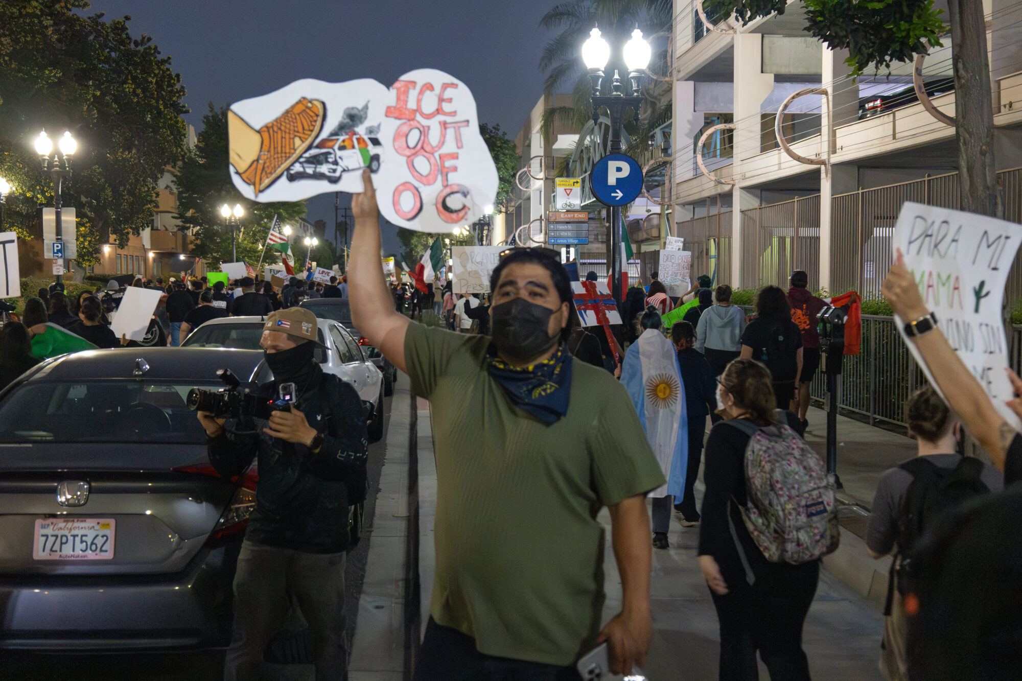 Protester holds sign with border patrol car getting crushed