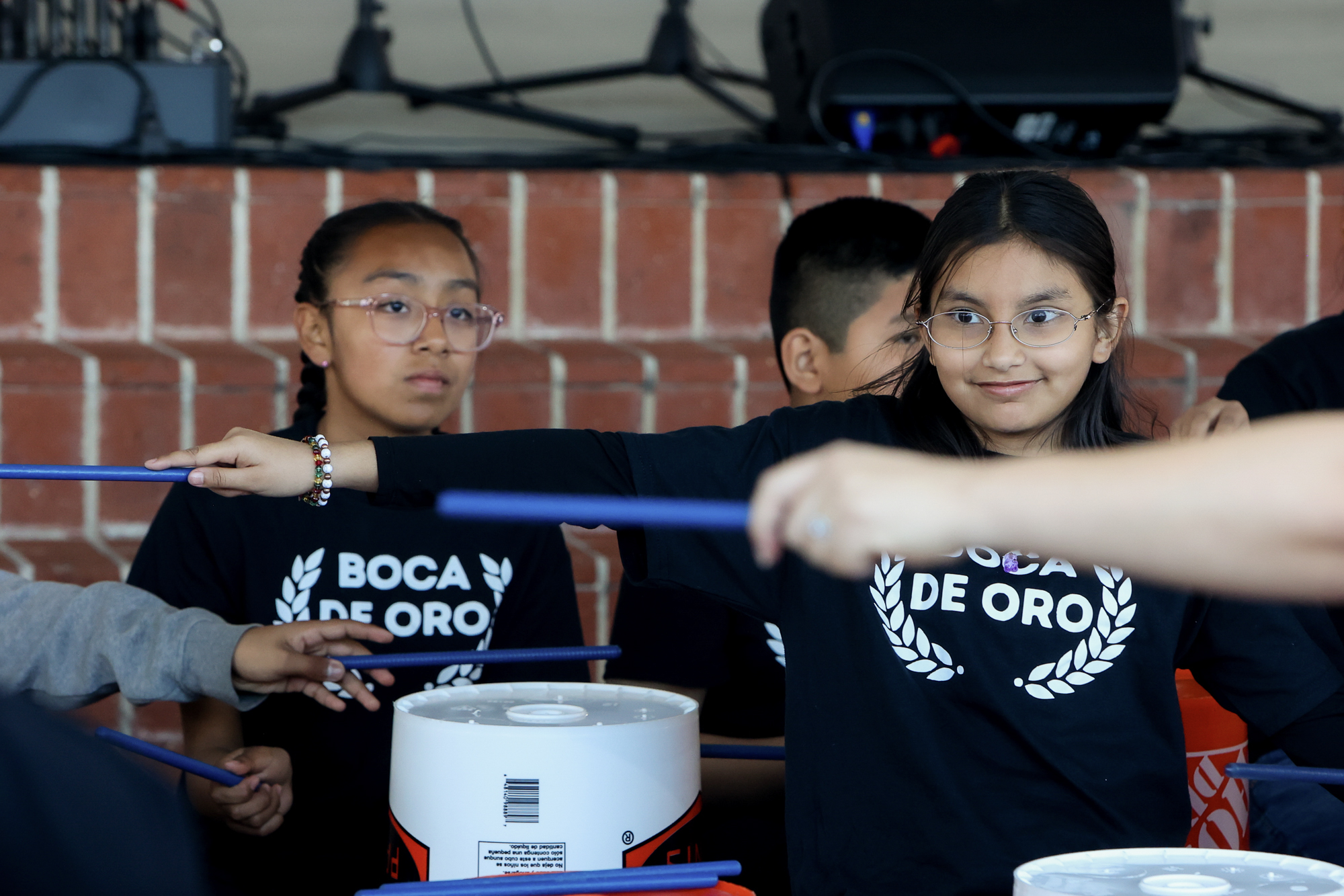 Youth group in Boca de Oro t-shirts drum on upside down paint buckets.