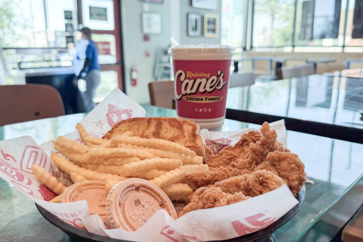 Chicken fingers, french fries, grilled bread and drink sitting on a counter.