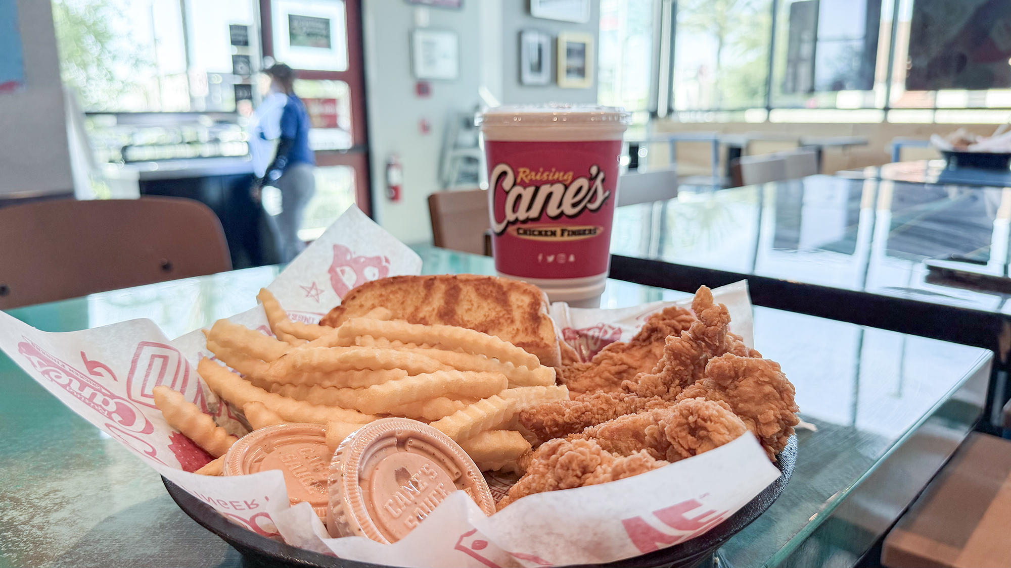 Chicken fingers, french fries, grilled bread and drink sitting on a counter.