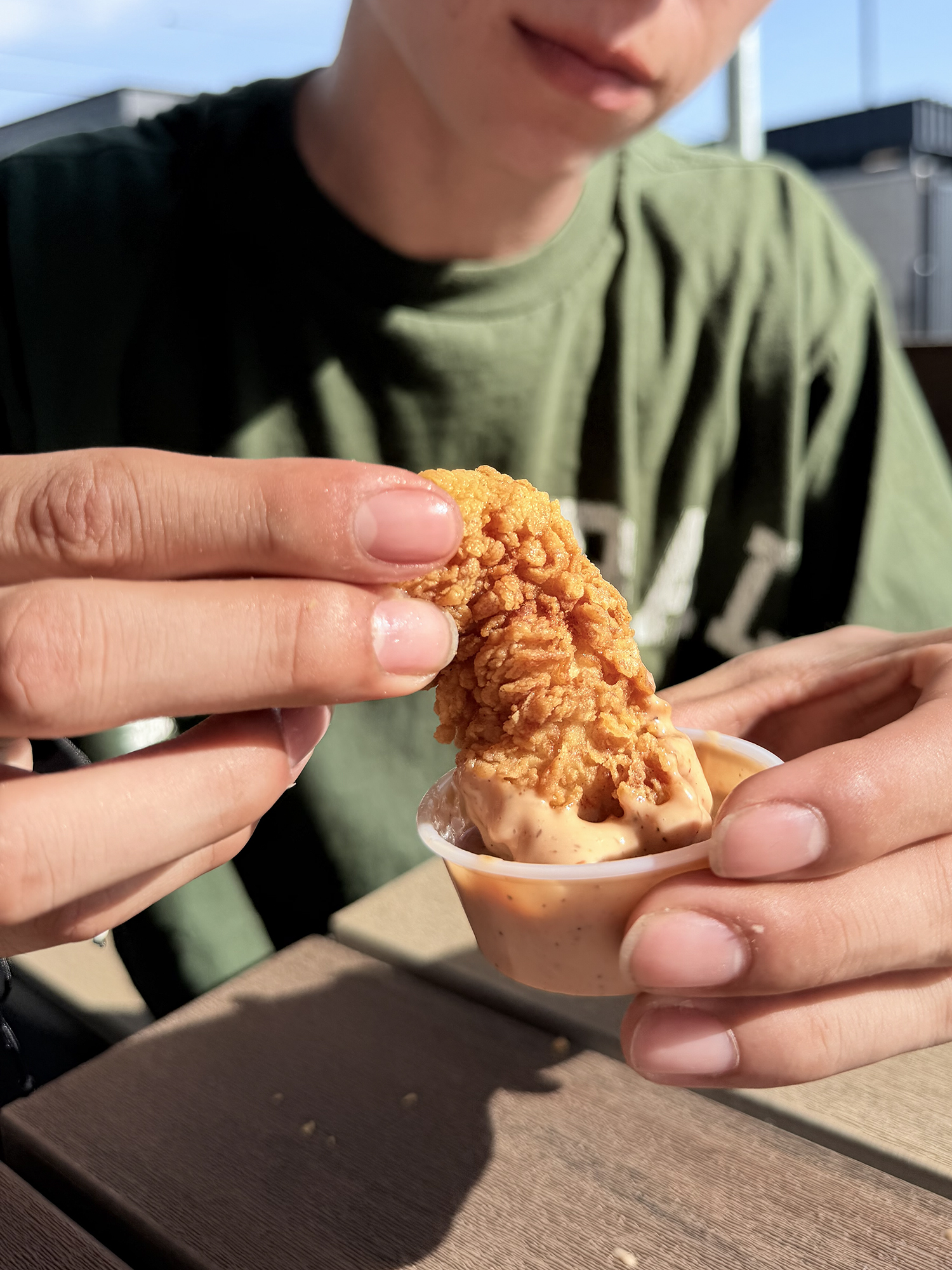 Dipping a chicken finger in canes sauce.