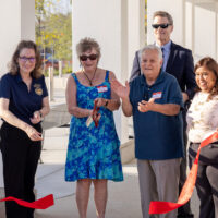 Three women and two men standing at ribbon cutting ceremony.