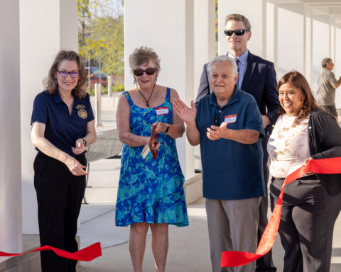 Three women and two men standing at ribbon cutting ceremony.