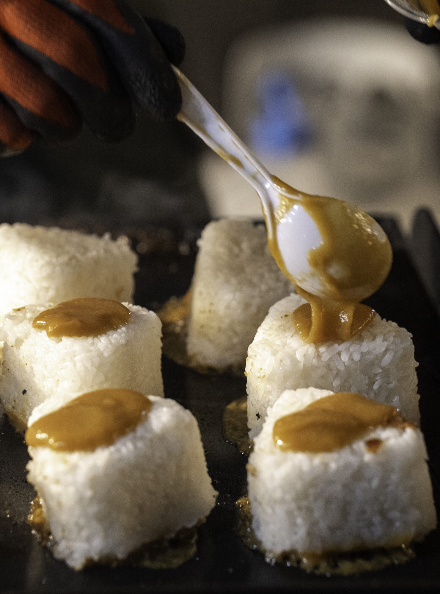 A miso glaze is dropped onto grilled rice balls.