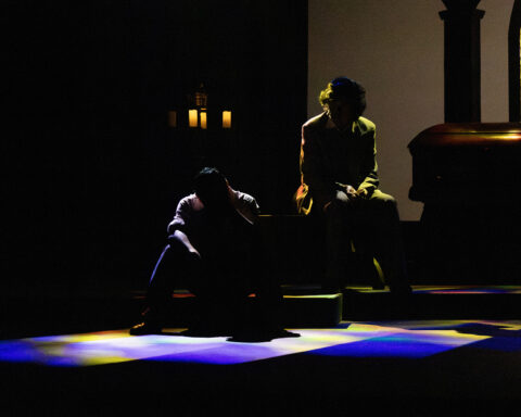Two silhouettes on a stage with some colored lighting