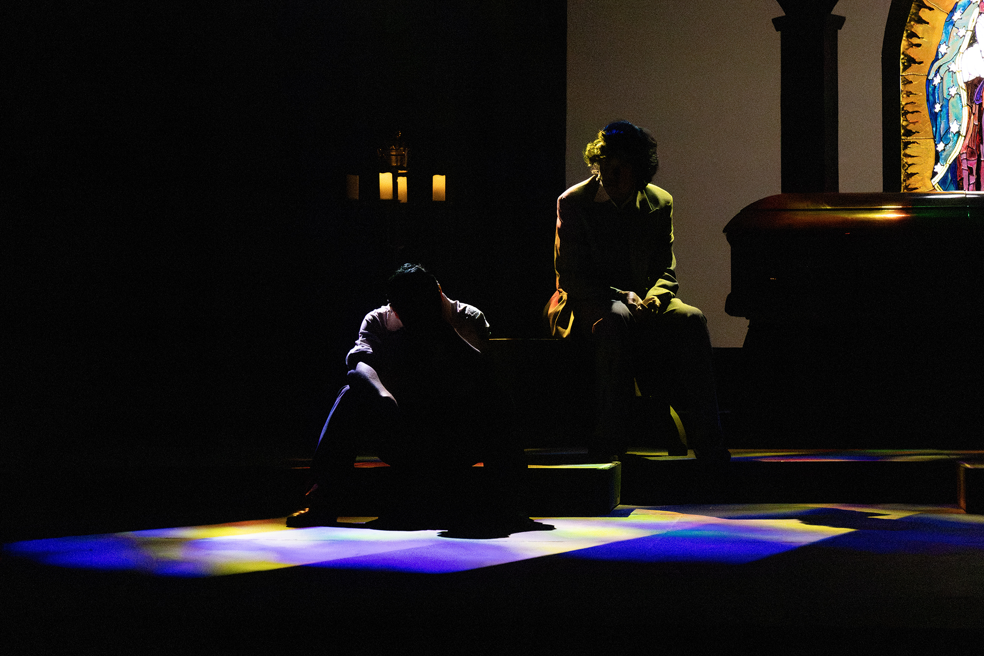 Two silhouettes on a stage with some colored lighting