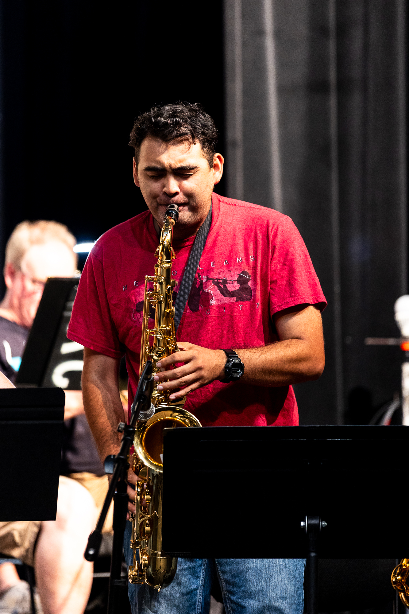 Man performs with tenor saxophone during jazz rehearsal.