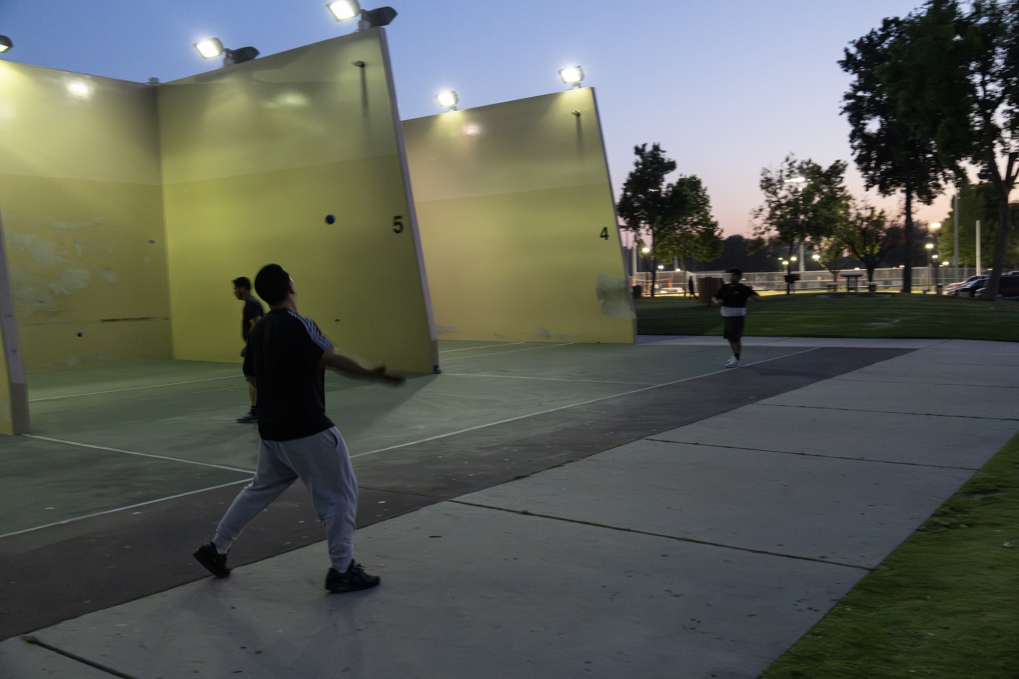 A man running to hit a ball before it goes out of bounds