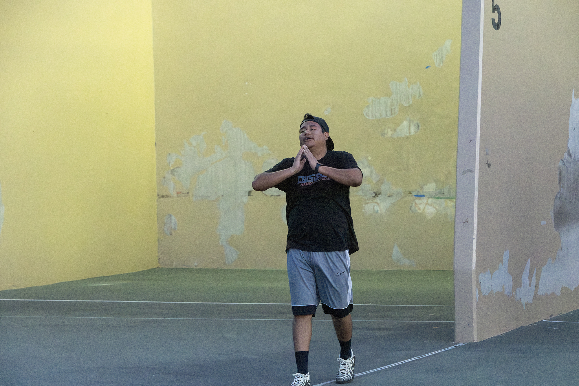 A man doing prayer hands at a handball court